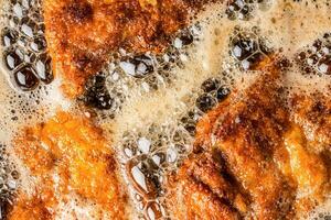 dettaglio di schnitzels nel briciole di pane frizzante nel frittura olio foto