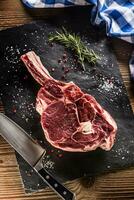 crudo Manzo tomahawk bistecca con sale Pepe e rosmarino su ardesia piatto foto