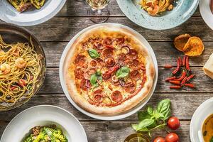 superiore di Visualizza pieno tavolo di italiano pasti su piatti e padella. Pizza pasta risotto la minestra e pesce verdura insalata foto