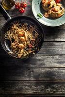 pasta spaghetti su piatto e padella con gamberetto pomodoro salsa pomodori e erbe aromatiche. italiano o mediterraneo cucina foto