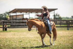 giovane cowgirl conduce sua cavallo durante un' cavalcata su un' ranch foto