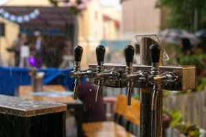 cromato rubinetti per bozza birra nel un' strada bar sotto il pioggia. foto