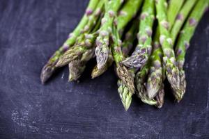 organico fresco crudo giardino asparagi closeup sul bordo nero dello sfondo. verdure verdi primaverili. foto