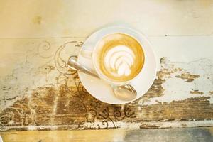 una tazza di caffè latte con un design a forma di fiore in cima al bar foto