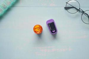 contenitore per pillole mediche e pulsossimetro sul tavolo foto