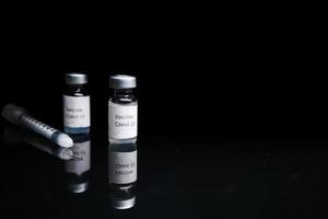 Close up del vaccino contro il coronavirus e la siringa su sfondo nero