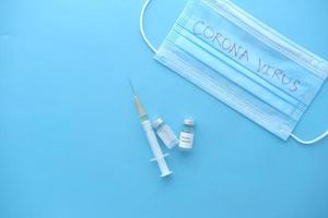 vista dall'alto del vaccino contro il coronavirus e della siringa su sfondo blu foto