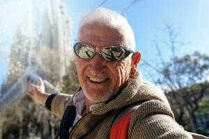 bello mezzo anziano uomo visitare sagrada famiglia, Barcellona - contento turista assunzione un' autoscatto nel il strada foto