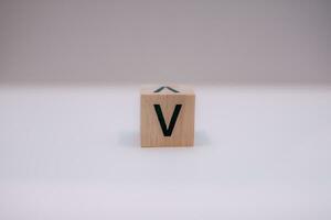 di legno bloccare scritto v con un' bianca sfondo, formazione scolastica concetto, vicino su. foto