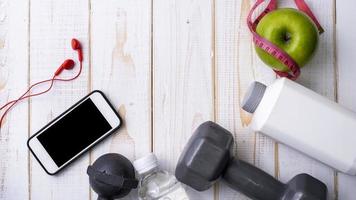 attrezzature per il fitness e alimenti salutari su sfondo di legno bianco foto