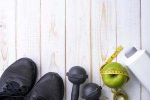 attrezzature per il fitness e alimenti salutari su sfondo di legno bianco foto