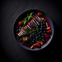 acai ciotola. frutta insalata con fragole e mirtilli nel un' nero ciotola su un' nero sfondo foto