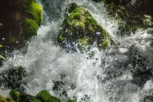 foto ravvicinata di una cascata fresca e pulita circondata da rocce ricoperte di muschio verde