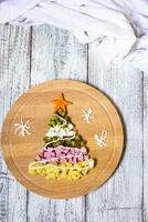 Natale albero a partire dal un' insalata olivier su taglio tavola su un' bianca di legno tavolo. superiore Visualizza con un' copia spazio. foto