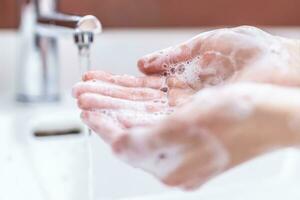 lavaggio mani con acqua e liquido sapone nel il bagno. igiene antivirus concetto foto