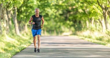 più vecchio uomo corre salita nel il natura durante un' estate giorno conservazione il suo fitness livello alto foto