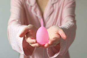 avvicinamento di un' donna Tenere un' silicone mestruale tazza. alternativa ecologico femminile igiene Prodotto durante mestruazione senza sprechi concetto foto