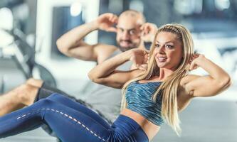 donna e uomo atletico coppia rafforzare addominale muscoli nel palestra. nucleo forza formazione esercizio foto