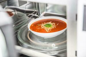 dentro Visualizza di nuovo pulito instancabile microonde forno con un' pomodoro la minestra nel bianca piatto foto