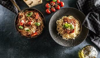 superiore di Visualizza italiano pasta spaghetti bolognese nel piatto e padella con pomodori e basilico foto