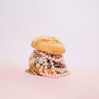 creativo Hamburger con gioielleria contro pastello rosa sfondo. foto