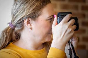 primo piano donna con una macchina fotografica in mano che scatta foto