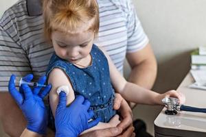una bambina con suo padre nell'ambulatorio della clinica viene vaccinata contro il coronavirus foto