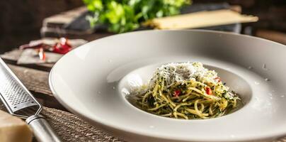 spaghetti aglio e olio con oliva olio, gralico, basilico, parmigiano formaggio, pomodori e peperoncini servito nel un' in profondità piatto foto