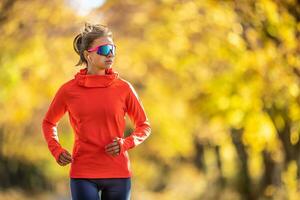 giovane femmina atleta nel abbigliamento sportivo corre nel il parco durante caldo indiano estate foto