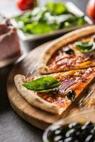 Pizza diavolo tradizionale italiano pasto a partire dal speziato salame peperoni chili cipolla olive e basilico foto