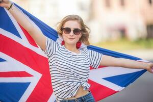 attraente contento giovane ragazza con il bandiera di il grande Gran Bretagna foto