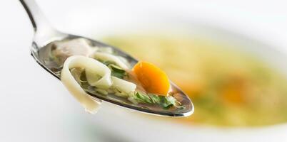 cucchiaio pieno di pollo o Manzo la minestra con tagliatelle carota e erbe aromatiche foto