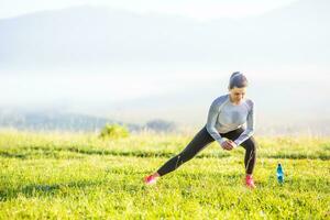 giovane fitness donna corridore allungamento gambe prima correre nel autunno natura foto