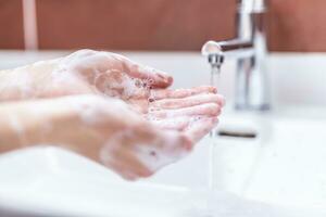 lavaggio mani con acqua e liquido sapone nel il bagno. igiene antivirus concetto foto