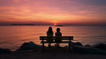 Due senza volto ragazze sedersi su un' panchina prospiciente calma acqua un' roccioso riva del mare e un' rosa cielo a sera persone comunicare su il orizzonte mentre navi vela a mare. silhouette concetto foto