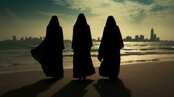 tre donne nel tradizionale capi di abbigliamento in piedi a dubai S spiaggia. silhouette concetto foto