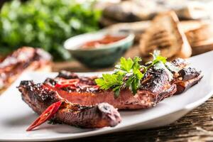 gustoso barbecue grigliato Maiale costolette con chili pepers e prezzemolo erbe aromatiche. foto