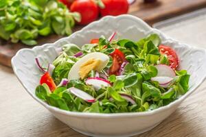 fresco primavera insalata con verde le foglie pomodori uovo ravanello rosso cipolla giovane piselli prosciutto feta formaggio e oliva olio foto