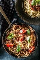 superiore di Visualizza italiano pasta spaghetti bolognese nel piatto e padella con pomodori e basilico foto