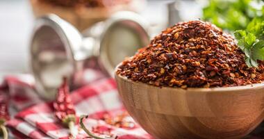 secco e schiacciato chili peperoni nel di legno bocce con prezzemolo erbe aromatiche foto