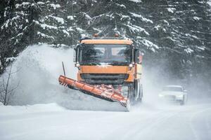 spazzaneve radura strada a partire dal neve nel il foresta con traffico liner su dietro a il camion foto