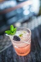 cocktail bevanda rovo con nero frutti di bosco e menta a bancone da bar nel notte club o ristorante foto