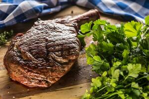 appena grigliato tomahawk bistecca su ardesia piatto con sale Pepe rosmarino e prezzemolo erbe aromatiche foto