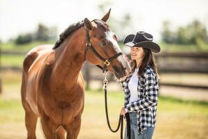 un' legame fra un' cavallo e un' giovane donna nel cowboy cappello su un' ranch all'aperto foto