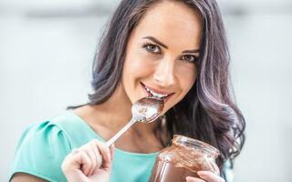 giovane bellissimo donna gode emotivamente cioccolato o Nocciole crema foto