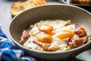 inglese prima colazione fritte Bacon prosciutto e uova nel ceramica padella foto