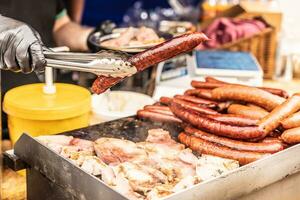 strada venditore detiene grande salsiccia di pinze durante un' vendita a il strada cibo giusto foto