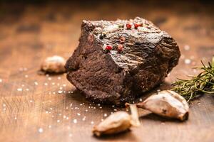 succoso Manzo bistecca con spezie e erbe aromatiche su di legno taglio tavola foto