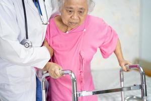 asiatico infermiere fisioterapista medico cura, aiuto e supporto anziano o anziana donna anziana paziente cammina con deambulatore in corsia ospedaliera, sano concetto medico forte.