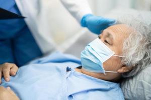 medico che utilizza lo stetoscopio per controllare la donna anziana asiatica anziana o anziana paziente che indossa una maschera facciale in ospedale per proteggere l'infezione covid-19 coronavirus.